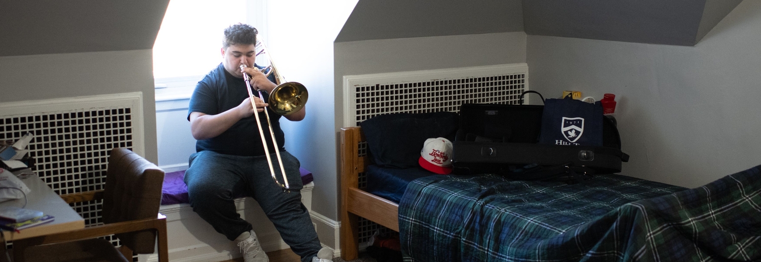 student playing trumpet in their dorm